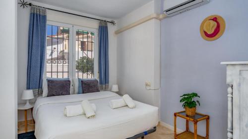 - une chambre avec un lit blanc et une fenêtre dans l'établissement Sunlit Retreat with Garden Haven, à Fuengirola