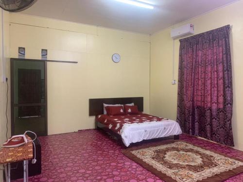 a bedroom with a bed and a window with pink curtains at Tina Homestay Budget in Ketereh