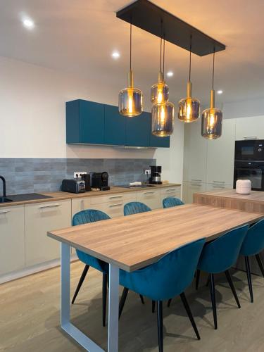 a kitchen with a wooden table and blue chairs at Luxe & Confort, Spacieux, Neuf, Clim et Central in Sète