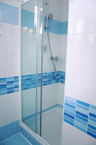 a glass shower in a bathroom with blue tiles at Apartman Dada in Krapinske Toplice