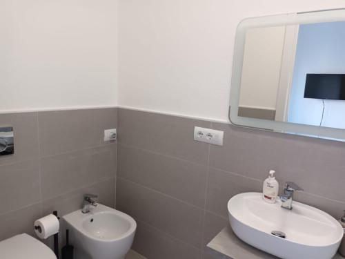 een badkamer met een wastafel, een spiegel en een toilet bij A Casa Nostra B&B in Cagliari