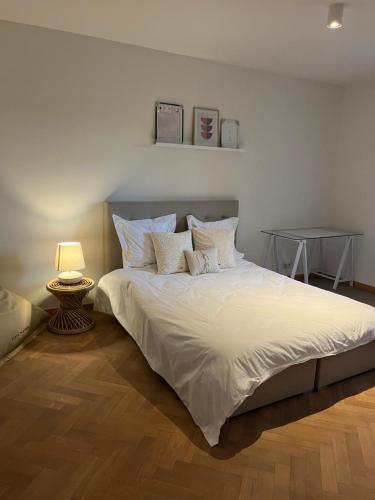 een bed met witte lakens en kussens in een slaapkamer bij Cosy Louvrex -Liège Francorchamps in Luik