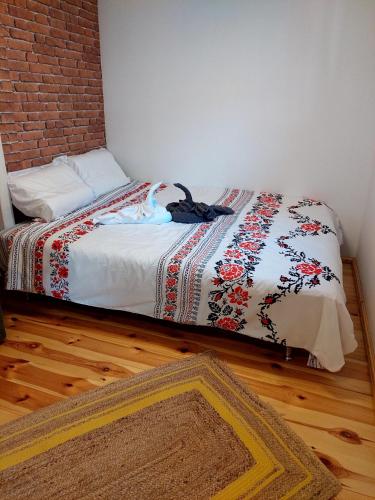 a bedroom with a bed with a blanket and a rug at Căsuța din poveste in Sohodol