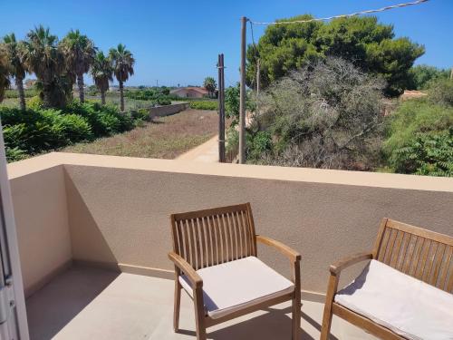 two chairs on a balcony with a view of palm trees at La casetta della Pigna Verde in Marsala