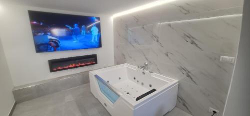 bagno con vasca bianca e TV a parete di Luxury Rooms a Santa Teresa di Gallura