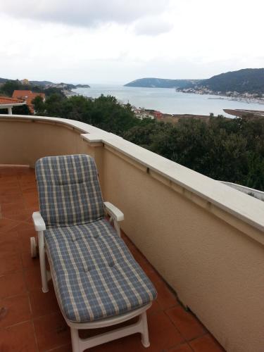 a chair sitting on a balcony overlooking the water at Apartments Dedić in Supetarska Draga