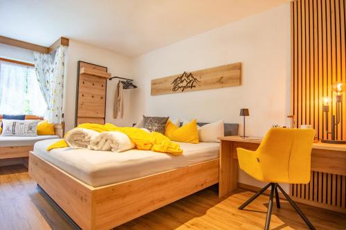 a bedroom with a bed with a desk and a yellow chair at Gästehaus Julia in Ischgl