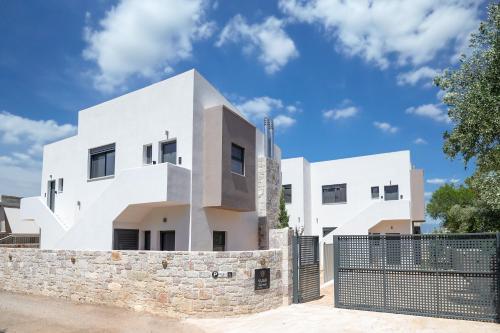 a white house with a stone wall at VUAR SUITES in Petalidi