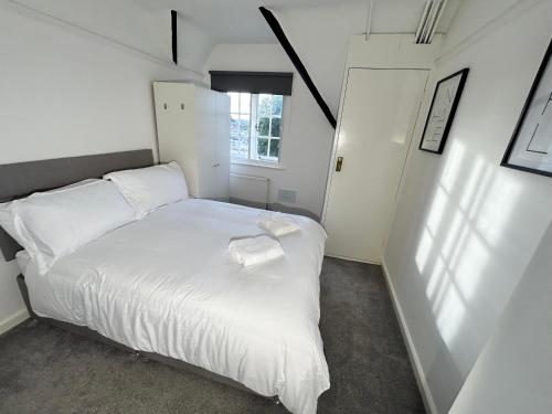 a white bed in a small room with a window at Down Ampney cottage in Down Ampney