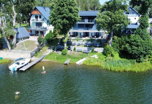 een rivier met een huis en een boot in het water bij Weranda in Wdzydze Kiszewskie