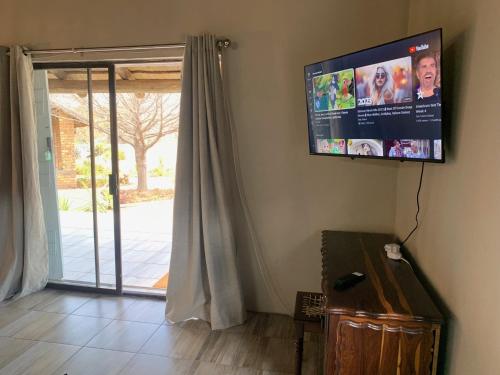 uma televisão de ecrã plano pendurada numa parede ao lado de uma porta em Sunset Cottages at Viva Connect, Cullinan em Meule
