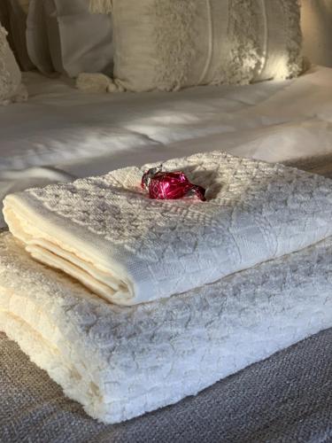 a bed with two white towels and a red flower on it at Sunset Guesthouse and Venue Cullinan in Meule