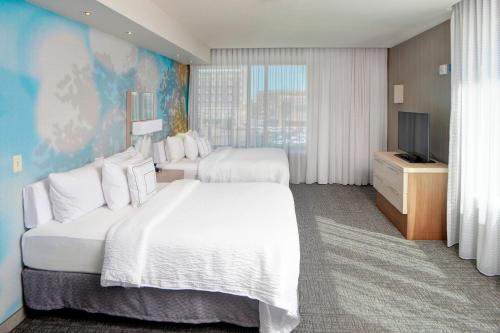 a hotel room with two beds and a television at Courtyard by Marriott Muncie at Horizon Convention Center in Muncie