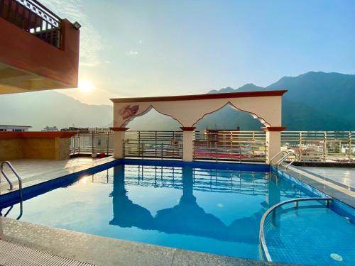 a pool on the roof of a hotel with mountains in the background at Arogyadham Retreat in Rishīkesh