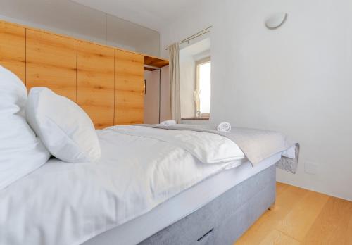 a bedroom with a white bed with a wooden headboard at revLIVING Cozy City Oldtown Appartement in Krems an der Donau