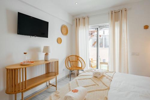 a bedroom with a bed and a tv on a wall at Coral Boutique Suites in Albufeira