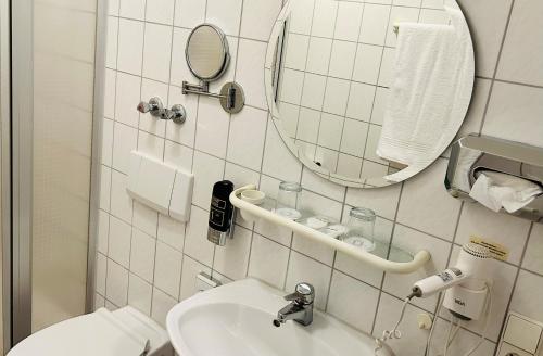 uma casa de banho com um WC, um lavatório e um espelho. em Adler Hotel Garni em Ostfildern