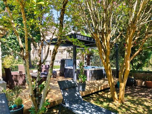 un patio trasero con cenador y 2 sillas y árboles en Les Tanalis - Chambres d'hôtes & Gîte, en Gurs