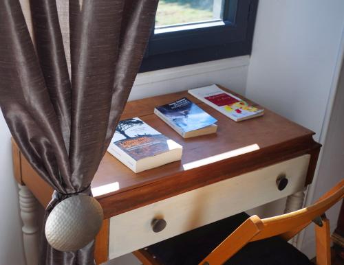 a wooden table with books on a desk with a window at Les Tanalis - Chambres d'hôtes & Gîte in Gurs