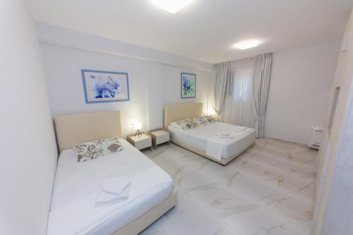 two beds in a room with white walls and marble floors at Luxury Vila 3 in Vlorë