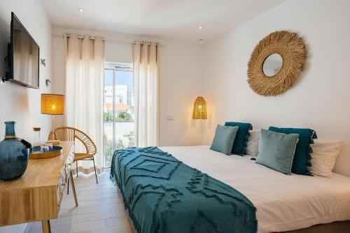 een slaapkamer met een bed, een tafel en een spiegel bij Coral Boutique Suites in Albufeira