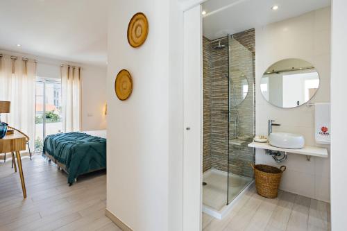 a bedroom with a bed and a bathroom with a shower at Coral Boutique Suites in Albufeira