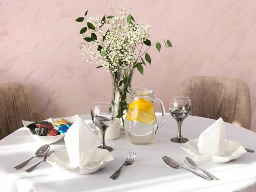 a table with a vase of flowers and a vase of orange juice at Люксовая квартира in Aktobe