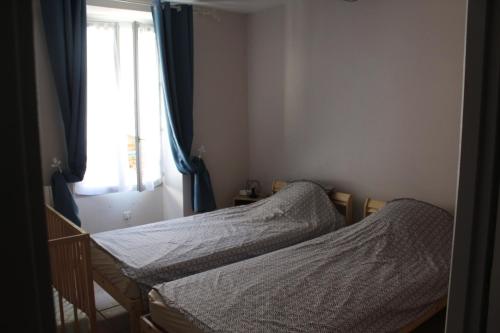 deux lits jumeaux dans une chambre avec fenêtre dans l'établissement Maison de village, à La Javie