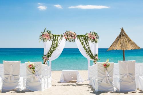 a wedding ceremony on the beach with chairs and an umbrella at Cormoran Residence in Villasimius