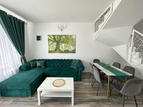 ein Wohnzimmer mit einem grünen Sofa und einem Tisch in der Unterkunft elisio - Maple House in Ghimbav