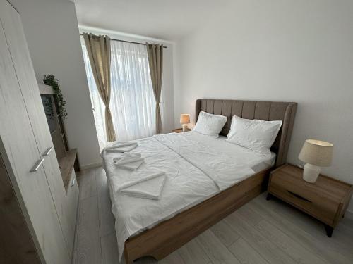 Schlafzimmer mit einem Bett mit weißer Bettwäsche und einem Fenster in der Unterkunft elisio - Maple House in Ghimbav