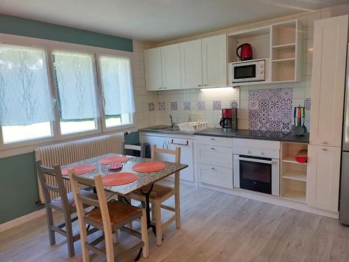 eine Küche mit einem Tisch und Stühlen sowie eine Küche mit weißen Schränken in der Unterkunft Appartement en Rez-de-jardin in Autrans