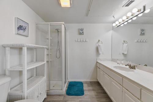 uma casa de banho branca com um chuveiro e um lavatório. em 3-level townhome w/ private pool & close to beach! em South Padre Island