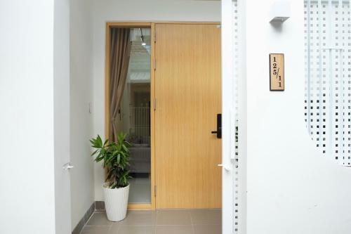 a wooden door with a plant in a room at Central, Minimalist and Cozy - Gau's House in Da Nang