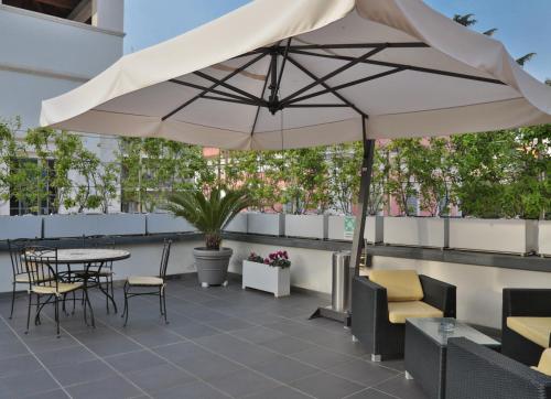 a patio with a table and chairs and an umbrella at Best Western Cinemusic Hotel in Rome