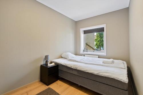 a small bedroom with a bed and a window at Ny sentral og moderne leilighet in Kristiansand