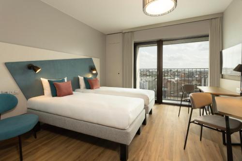 アントワープにあるAparthotel Adagio Antwerp City Centerのベッド2台とテーブルが備わるホテルルームです。