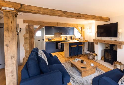 a living room with a blue couch and a kitchen at Cotswold cottage with hot tub in Bledington