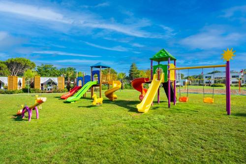 a playground with colorful slides on a grass field at Granada Luxury Belek - Family Kids Concept in Belek