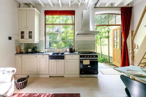 a kitchen with white cabinets and a black stove at Carriage House in quiet ecological garden in Antwerp