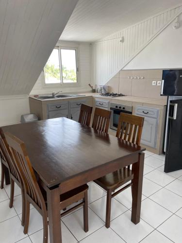 uma cozinha com uma mesa de jantar em madeira e cadeiras em ti sable appartement à 5 minutes de la mer em Saint-Joseph