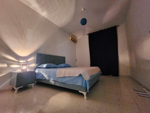 a bedroom with a bed with a blue bedspread and a window at La maison enchantée in La Marsa