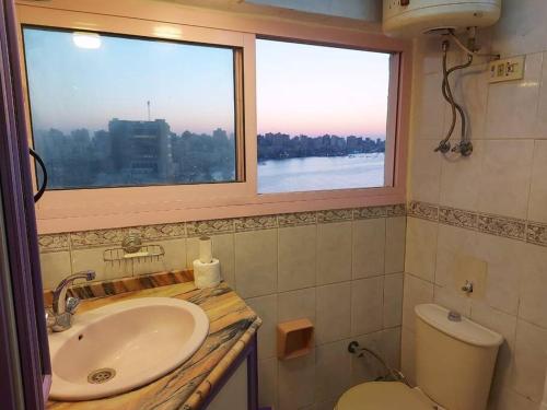a bathroom with a sink and a toilet and two windows at City center with amazing sea view in Alexandria