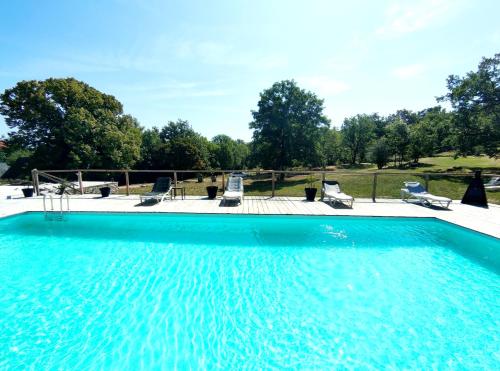 une grande piscine avec des chaises sur la terrasse dans l'établissement Le domaine du Quercy, à Padirac