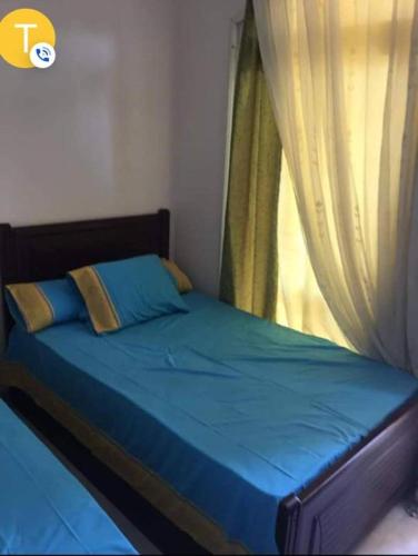 a bedroom with a bed with blue sheets and a window at شاليه قريه فارما بيتش ريزورت in Al Ḩammād