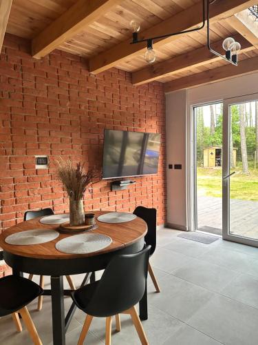 a dining room with a table and a tv on a brick wall at Bliżej Lasu in Śliwice
