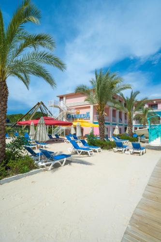 a beach with chairs and palm trees and a hotel at Granada Luxury Belek - Family Kids Concept in Belek