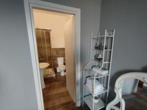 a bathroom with a toilet and a shelf with towels at Benedettini House in Catania