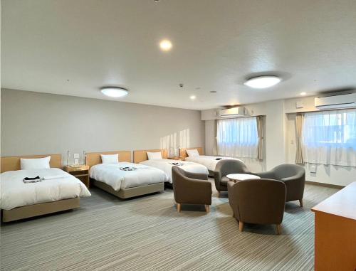 a hotel room with three beds and chairs at Sun Plaza Hotel Fuji Lake Yamanaka in Yamanakako