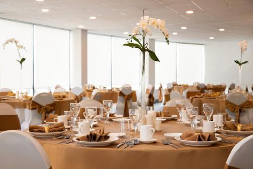 a long table with plates and glasses and a vase with flowers at Holiday Inn Philadelphia Arpt-Stadium Area by IHG in Philadelphia